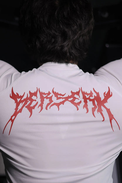 Person wearing a white t-shirt with red text on the back, standing against a dark background.